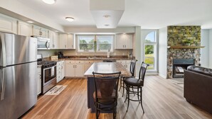 A modern kitchen with a central island, stainless steel appliances, and a stone fireplace. - 'heaven on the Hill' Retreat w/ Deck + Gas Grill! (Frewsburg)