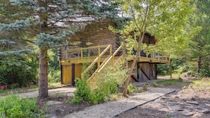 Une cabane rustique en rondins de bois, avec un escalier en bois menant à un balcon.