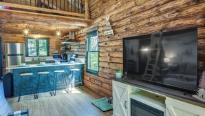 L’intérieur d’une cabane en rondins comprend une cuisine, un coin bar et un grand téléviseur.