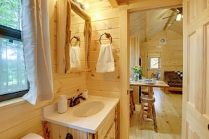 A wooden cabin interior with a bathroom featuring a sink, mirror, and towel rings. - Stunning Mtn Views: Middlebury Center Retreat! (Osceola)