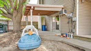 A backyard with a blue inflatable boat, a tree, a fence, and a house with an attached garage. - Bath Vacation Rental Condo w/ Pool Access! (Bath)