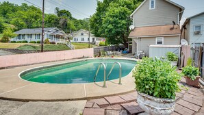 A residential swimming pool with a concrete deck, surrounded by houses and a large tree. - Bath Vacation Rental Condo w/ Pool Access! (Bath)