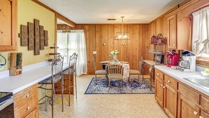 A kitchen with wooden cabinets, a dining table with chairs, a chandelier, and a coffee maker. - 6 Mi to Scottsboro: Pet-friendly Cabin Apt (Hollywood)
