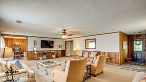 A spacious living room with a high ceiling, a ceiling fan, and a large window. There are two sofas, a coffee table, and a dining table with chairs. - 6 Mi to Scottsboro: Pet-friendly Cabin Apt (Hollywood)