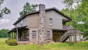A two-story log cabin with a stone chimney, a porch, and a staircase leading to a balcony. - 6 Mi to Scottsboro: Pet-friendly Cabin Apt (Hollywood)