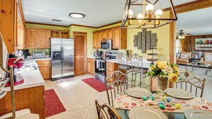 A spacious kitchen with wooden cabinets, stainless steel appliances, and a dining area with a floral tablecloth. - 6 Mi to Scottsboro: Pet-friendly Cabin Apt (Hollywood)
