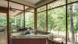Ein Whirlpool in einer Holzhütte mit großen Fenstern mit Blick auf einen Wald.