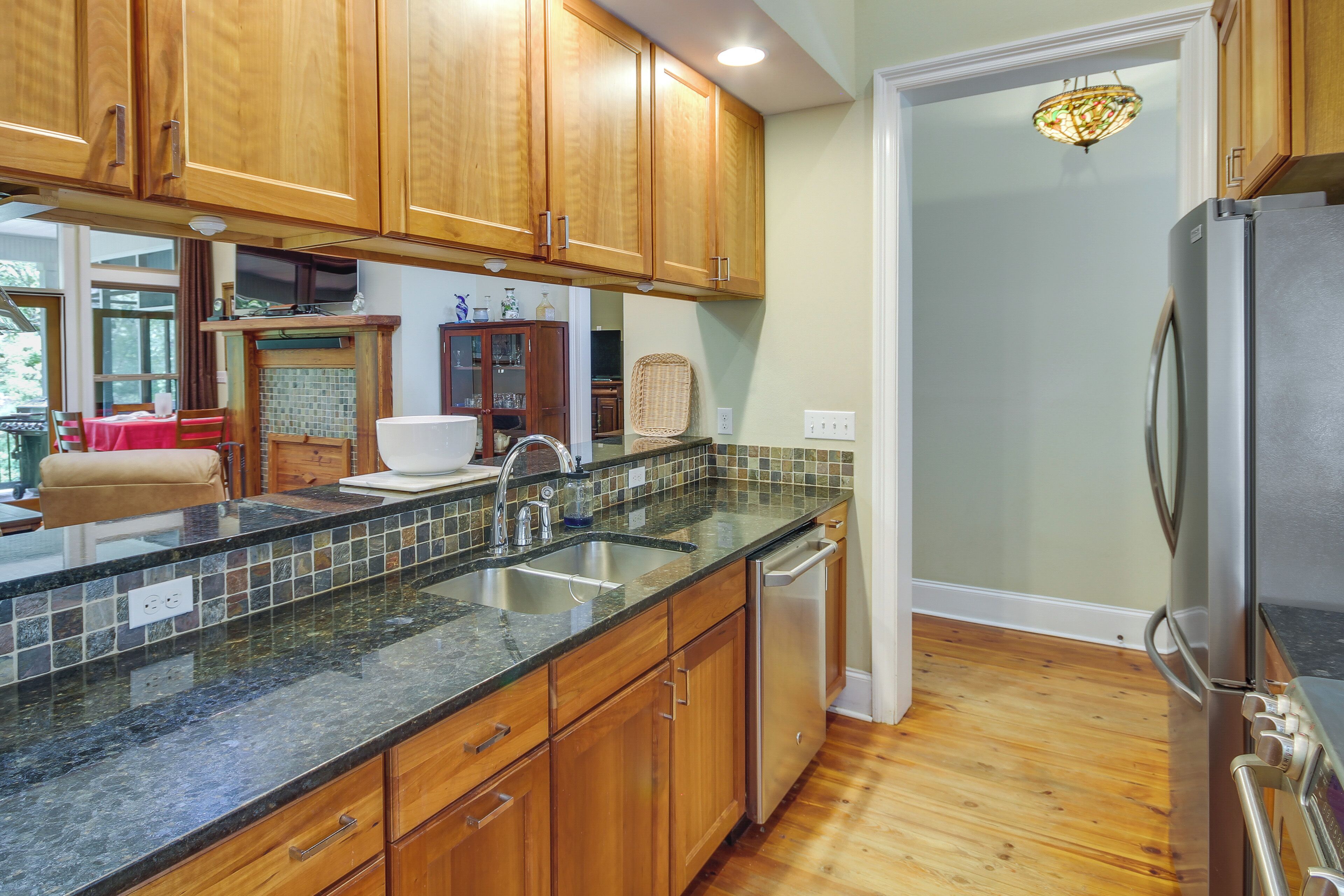 A kitchen with wooden cabinets, a granite countertop, a stainless steel refrigerator, and a dishwasher.