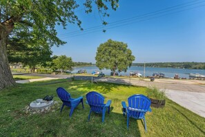 A lakeside view with blue chairs, a tree, and boats in the background. - Delavan Retreat w/ Patio on Turtle Lake! (Delavan)
