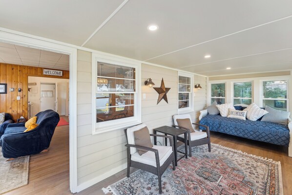A cozy living area with a blue sofa, two chairs, a rug, and a 'Welcome' sign. - Delavan Retreat w/ Patio on Turtle Lake! (Delavan)
