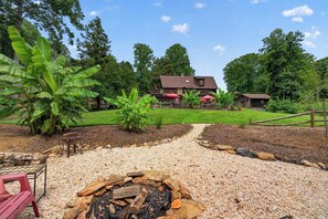 A backyard with a fire pit, a dining area, and a house with a red umbrella. - Hickory Hideaway: Pet-friendly Haven w/ Fire Pit! (Hickory)