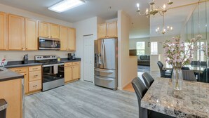 A modern kitchen with wooden cabinets, stainless steel appliances, and a marble countertop. - Owings Mills Townhouse: 8 Mi to Liberty Reservoir! (Owings Mills)