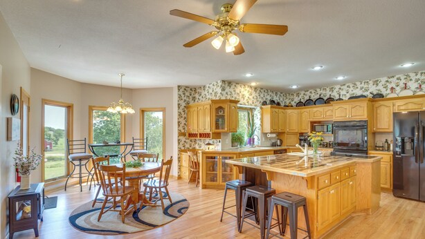 A spacious kitchen with wooden cabinets, a central island, and a ceiling fan. - Sibley Home w/ Game Room & Expansive Yard! (Sibley)