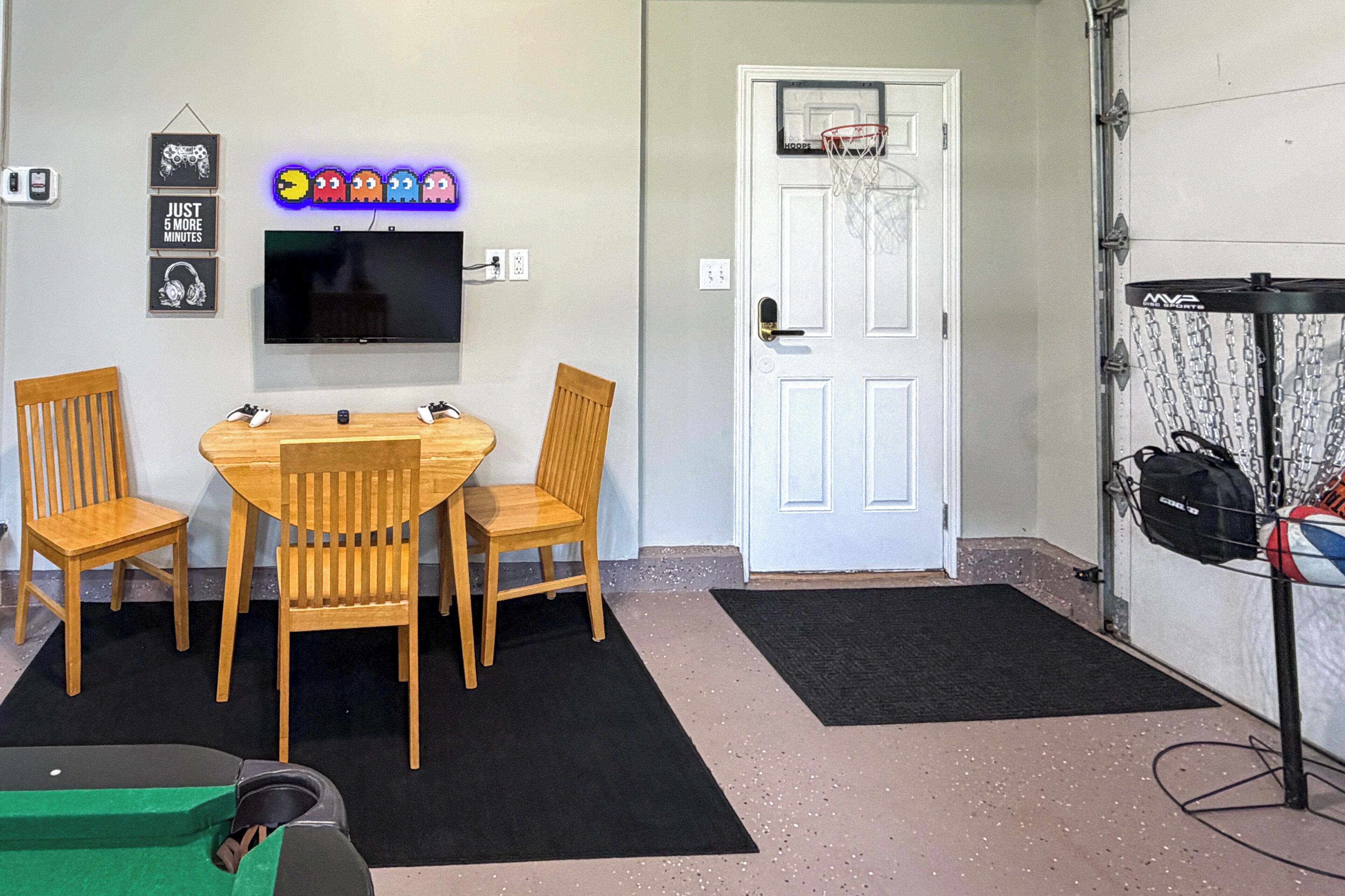 Una habitación con televisión, sillas de madera, aro de baloncesto y una puerta.