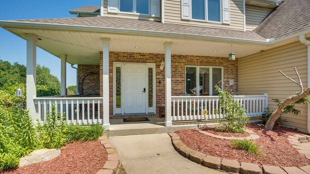 A two-story house with a covered porch, brick exterior, and a front door. - Sibley Home w/ Game Room & Expansive Yard! (Sibley)