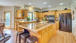 A spacious kitchen with wooden cabinets, a large island, stainless steel appliances, and a window providing natural light. - Sibley Home w/ Game Room & Expansive Yard! (Sibley)