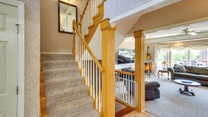 A staircase with wooden railings and carpeted steps leading to a living area with a sofa, coffee table, and a television. - Sibley Home w/ Game Room & Expansive Yard! (Sibley)