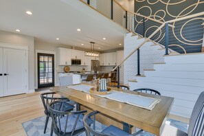 A modern kitchen with white cabinets, a wooden dining table, and a staircase with a unique design. - Modern Lake Ontario Escape w/ Beach Access! (Henderson)