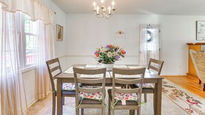 A dining room with a table set for four, a chandelier, and a floral centerpiece. - Peaceful Chatham Home w/ Grill & Deck (Chatham)