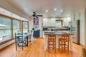 A modern kitchen with white cabinets, a stainless steel refrigerator, and a dining area with wooden chairs and a table. - Pet-friendly Union Vacation Rental With Pool! (Burlington)