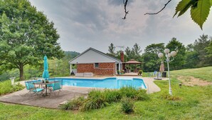 Una casa con piscina, un patio con sillas y un pabellón.