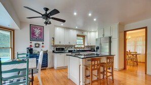 Una cocina moderna con armarios blancos, una isla central y un ventilador de techo.