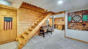 A wooden staircase with a wooden table and dartboards in a room with a high ceiling and wooden walls. - Alexandria Cabin w/ Patio, Grill & Deck (Bristol)