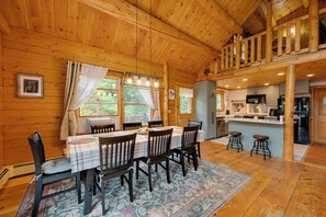 A wooden cabin interior with a dining area, kitchen, and a loft bedroom. - Alexandria Cabin w/ Patio, Grill & Deck (Bristol)