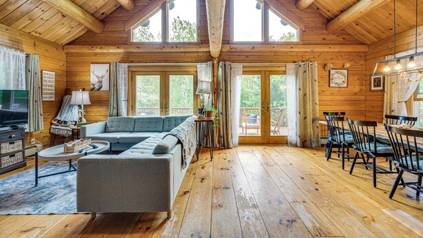 A spacious cabin with a large living area, a sofa, a dining table with chairs, and a television. - Alexandria Cabin w/ Patio, Grill & Deck (Bristol)