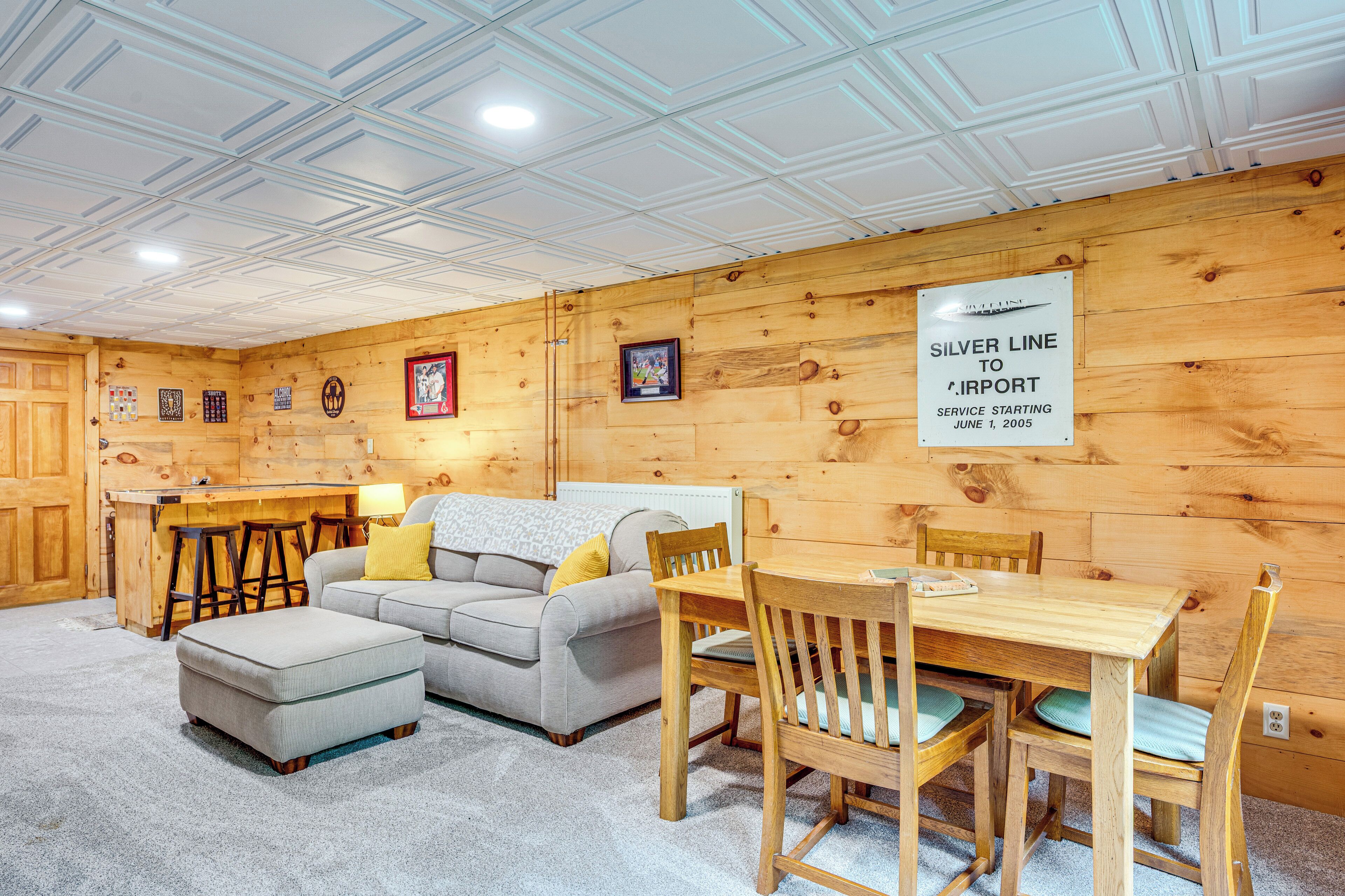 A cozy room with a wooden interior, a sofa, a dining table with chairs, and a sign indicating a service to the airport starting June 1, 2005.
