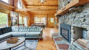 A cozy cabin interior with a stone fireplace, wooden ceiling, and a large sectional sofa. - Alexandria Cabin w/ Patio, Grill & Deck (Bristol)