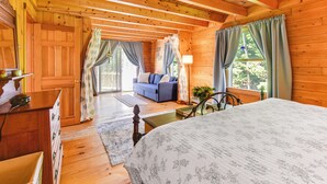A wooden cabin bedroom with a bed, a blue sofa, and a wooden dresser. - Alexandria Cabin w/ Patio, Grill & Deck (Bristol)