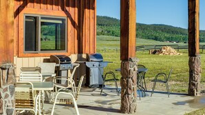 An outdoor patio with a grill, chairs, and a stone pillar. - Cozy Cora Studio Cabin w/ Wind River Mtn Views (Cora)