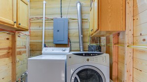 A compact laundry room with wooden walls, a washing machine, and a dryer. - Cozy Cora Studio Cabin w/ Wind River Mtn Views (Cora)