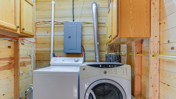 Une petite buanderie aux murs en bois, équipée d’un lave-linge et d’un sèche-linge.