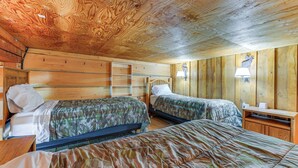 Une cabane avec deux lits, des murs en bois et un plafond avec des poutres apparentes.