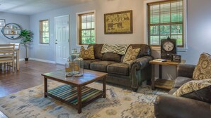 A living room with a leather couch, wooden coffee table, and a clock on a side table. - Searcy Vacation Rental w/ Deck & Water Views! (Searcy)