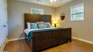 A bedroom with a wooden bed, two windows, a ceiling fan, and a nightstand with a lamp. - Searcy Vacation Rental w/ Deck & Water Views! (Searcy)