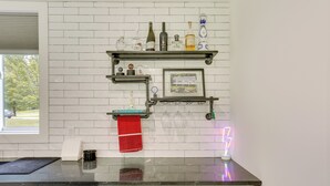 A kitchen with white brick backsplash, black countertop, and shelves with bottles and a framed picture. - Lakefront Catskills Container Home: Private Lake (Swan Lake)