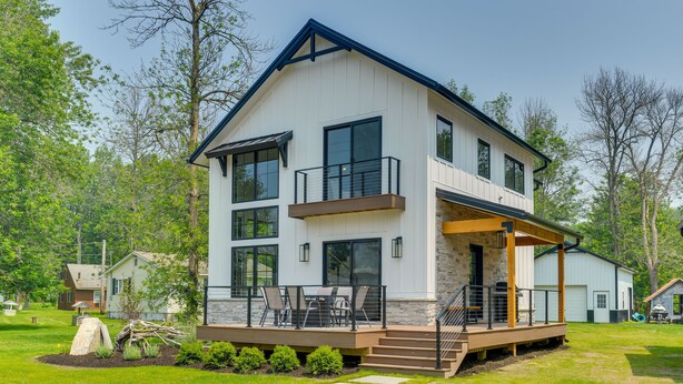 A modern two-story house with a balcony, a deck, and a stone foundation. - Spacious Lake Ontario Getaway: Steps to Beach! (Henderson)
