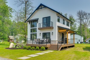 Une maison moderne à deux étages, dotée d’un balcon, d’une terrasse et de fondations en pierre.