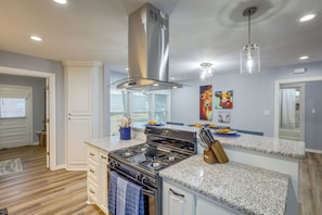 A modern kitchen with a stainless steel range hood, granite countertops, and a built-in oven.