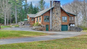 Une cabane en rondins avec une cheminée en pierre, une porte verte et un mur en pierre.