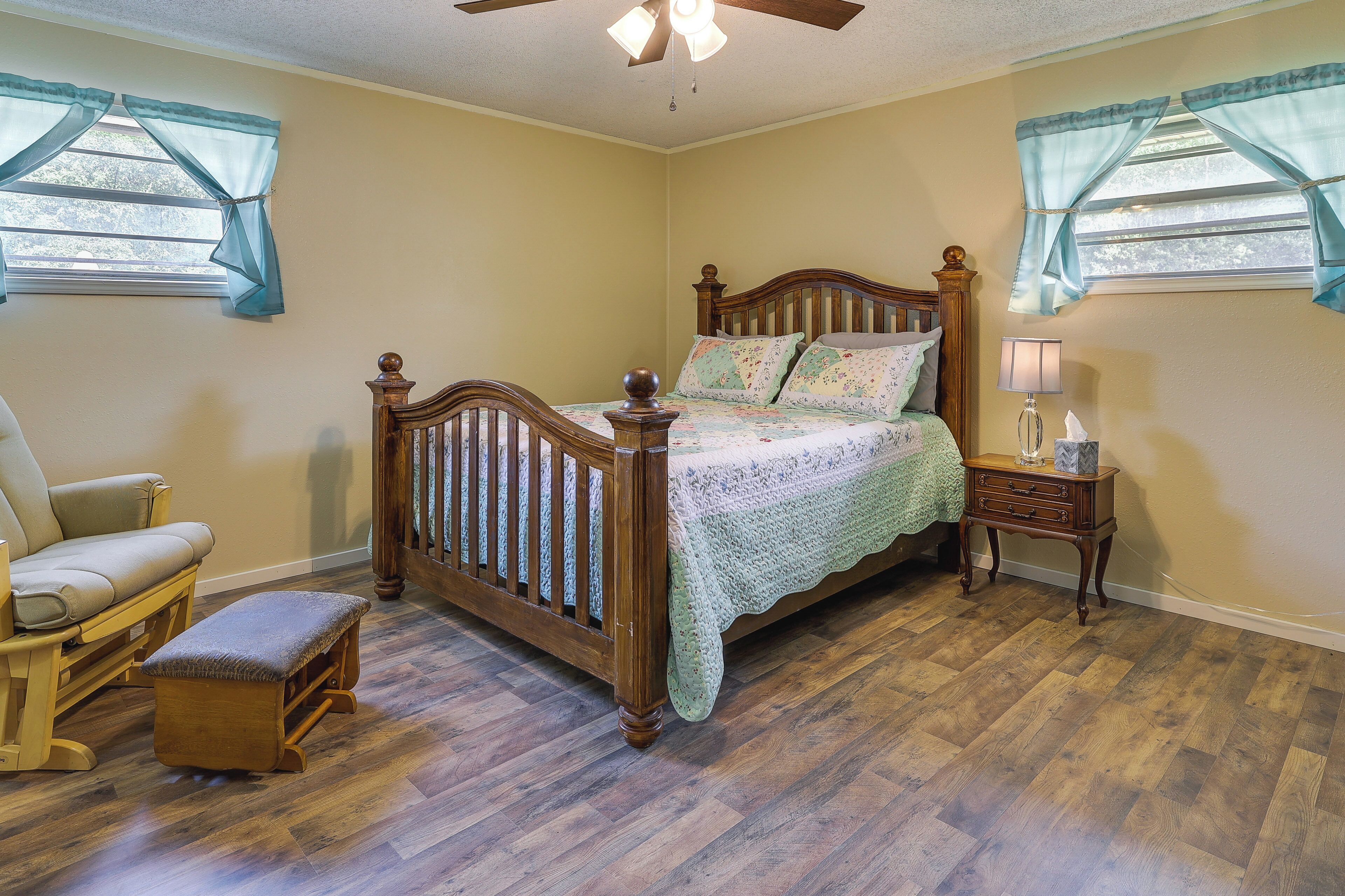 A bedroom with a wooden bed, a nightstand, a chair, and a bench.