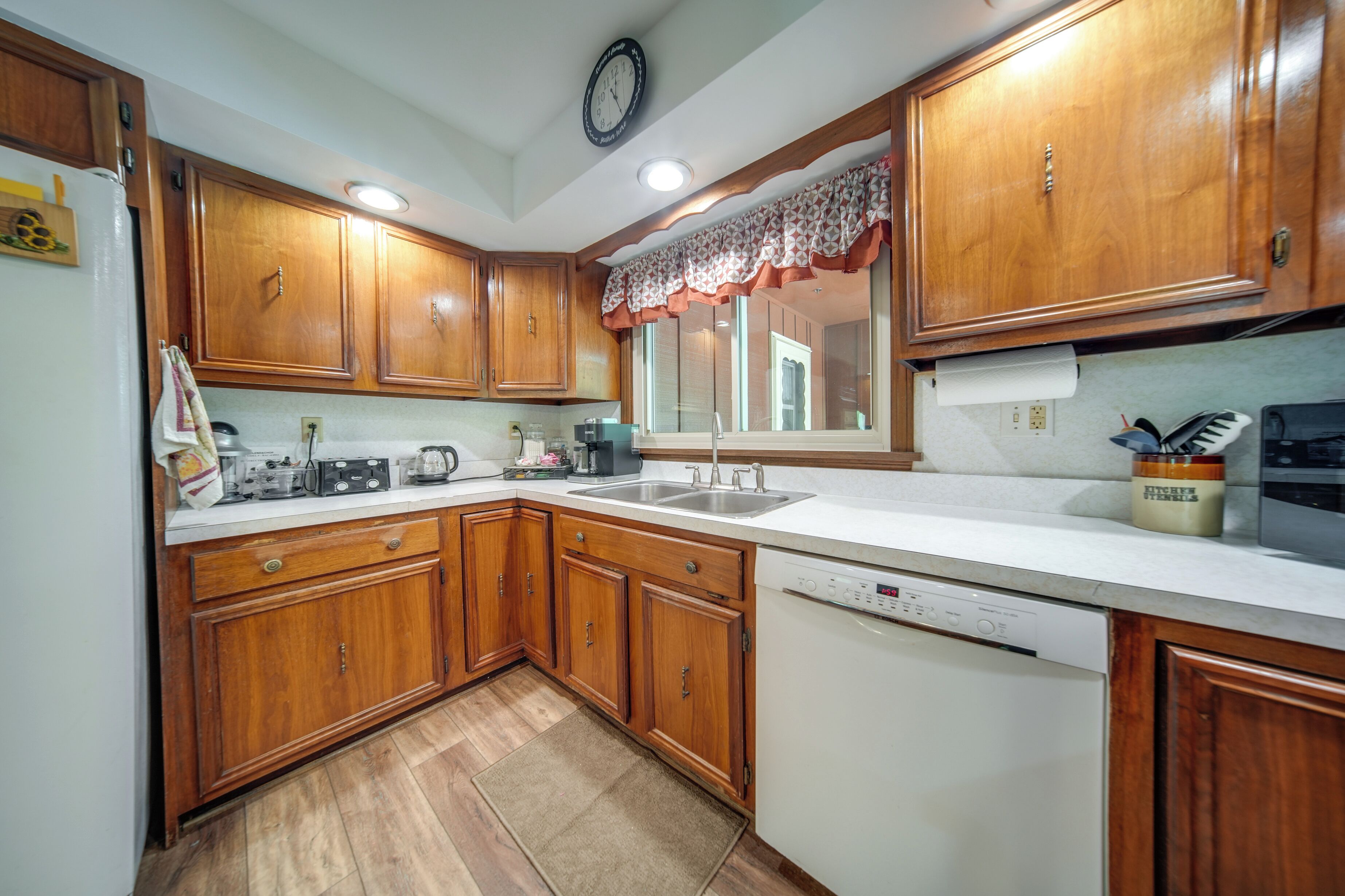 A kitchen with wooden cabinets, a white countertop, a sink, and a dishwasher.