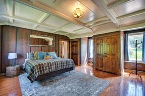 Une chambre spacieuse avec un grand lit, une armoire en bois et une vue sur l’extérieur par une fenêtre.