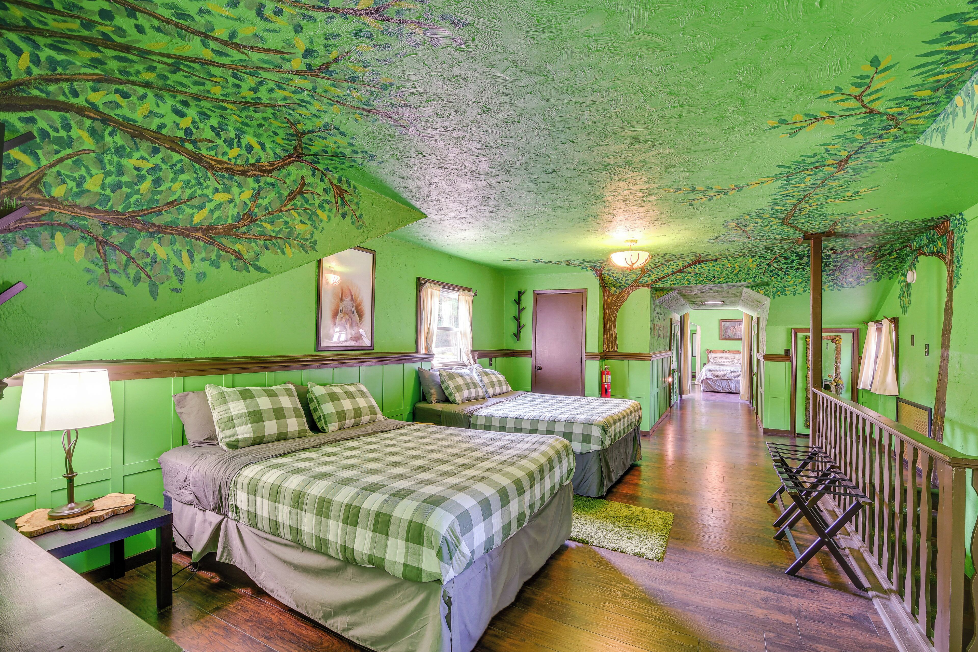 A room with two beds, a wooden floor, and green walls.