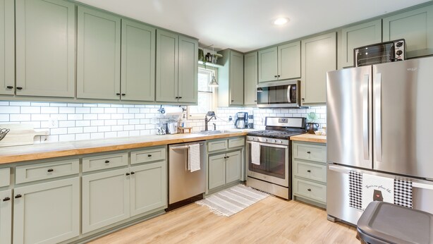 A kitchen with light green cabinets, a stainless steel refrigerator, a microwave, and a stove. - Pet-friendly Alabama Retreat w/ Deck & Patio! (Moody)