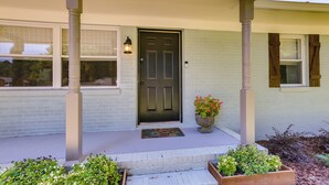 A house with a front porch, a dark front door, and a potted plant near the entrance. - Pet-friendly Alabama Retreat w/ Deck & Patio! (Moody)