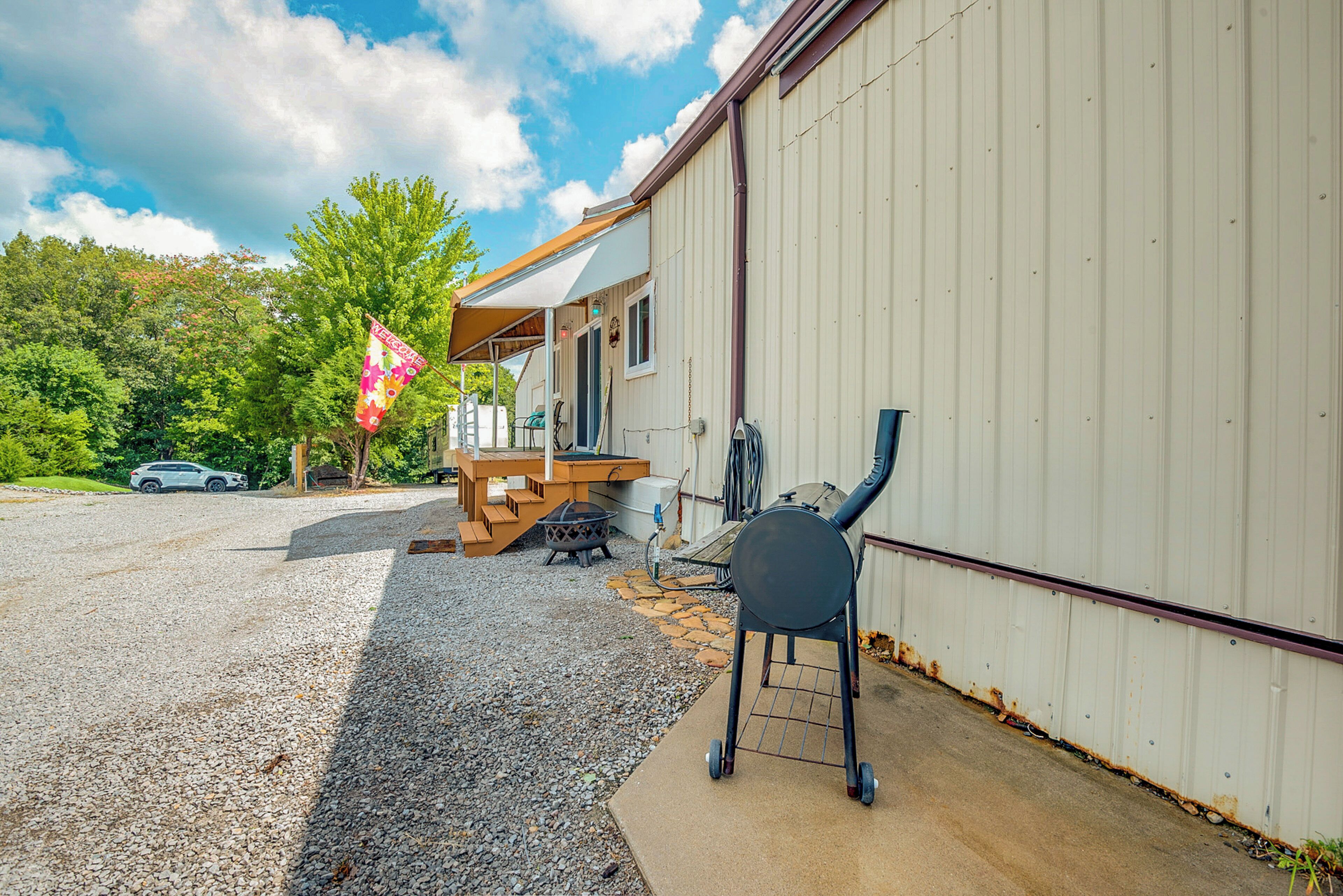 A building with a gravel driveway, a barbecue grill, and a flag.
